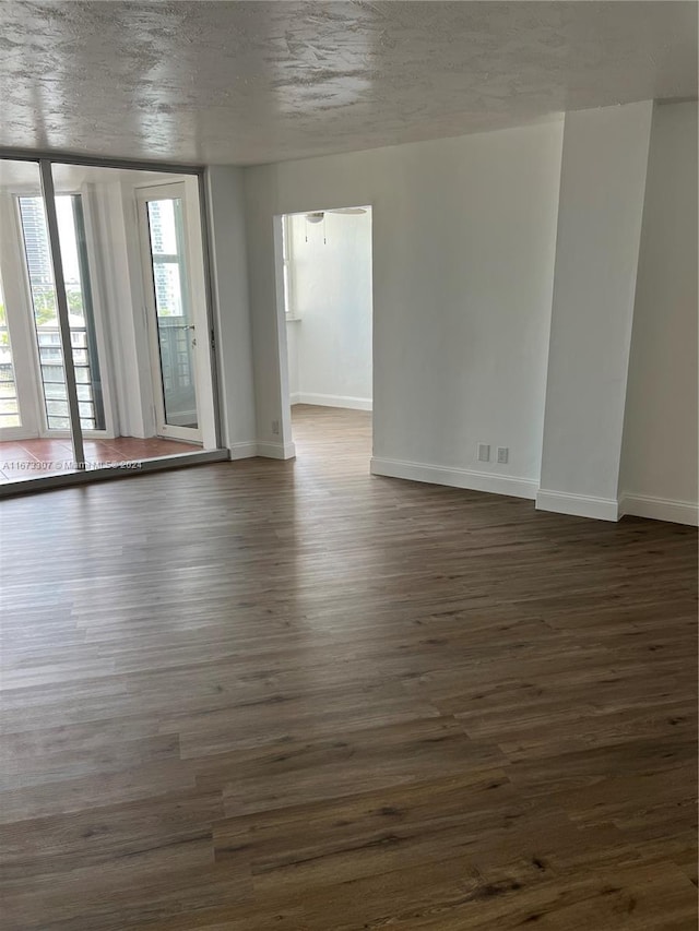 100 Golden Isles Dr Unit 605, Hallandale Beach, FL 33009 - unfurnished room featuring baseboards, a textured ceiling, and dark wood finished floors