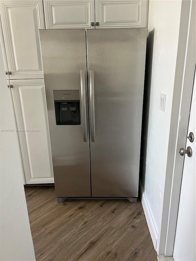 interior details with white cabinets, stainless steel refrigerator with ice dispenser, and dark wood-type flooring