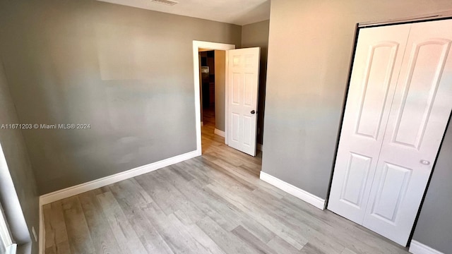 unfurnished bedroom with light hardwood / wood-style flooring and a closet