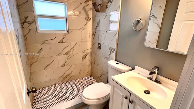 bathroom featuring vanity, a tile shower, and toilet