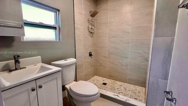 bathroom with toilet, vanity, tile patterned floors, and tiled shower