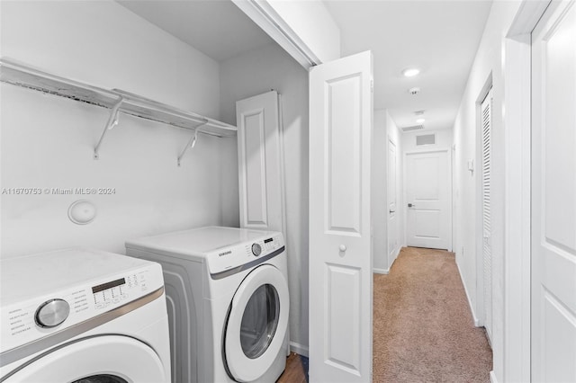 laundry room featuring light colored carpet and washer and clothes dryer