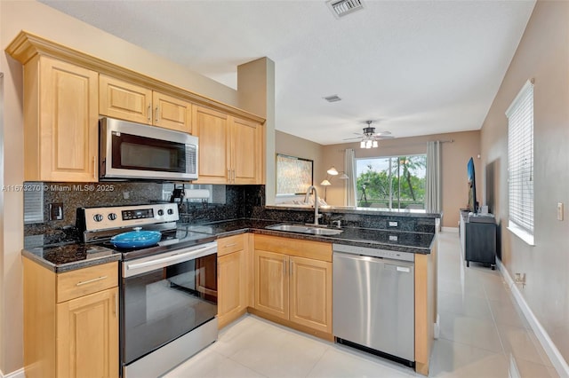 kitchen with sink, light tile patterned floors, kitchen peninsula, and appliances with stainless steel finishes