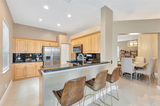 kitchen with kitchen peninsula, light brown cabinets, tasteful backsplash, and stainless steel appliances