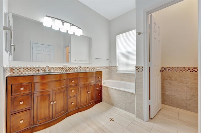 bathroom featuring tile walls, tile patterned flooring, tiled bath, and vanity