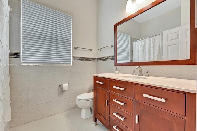 bathroom with toilet, tile patterned flooring, vanity, and tile walls