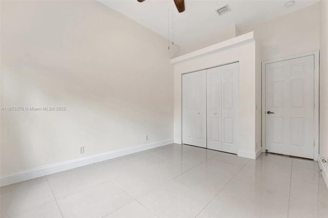 unfurnished bedroom featuring lofted ceiling, light tile patterned flooring, a closet, and ceiling fan