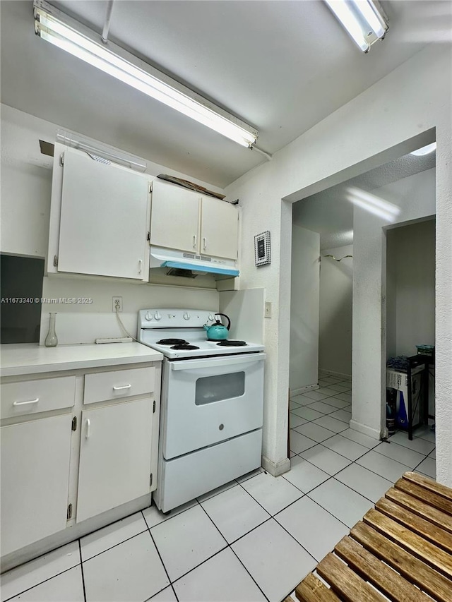 kitchen with light tile patterned floors, white electric range oven, light countertops, white cabinets, and under cabinet range hood