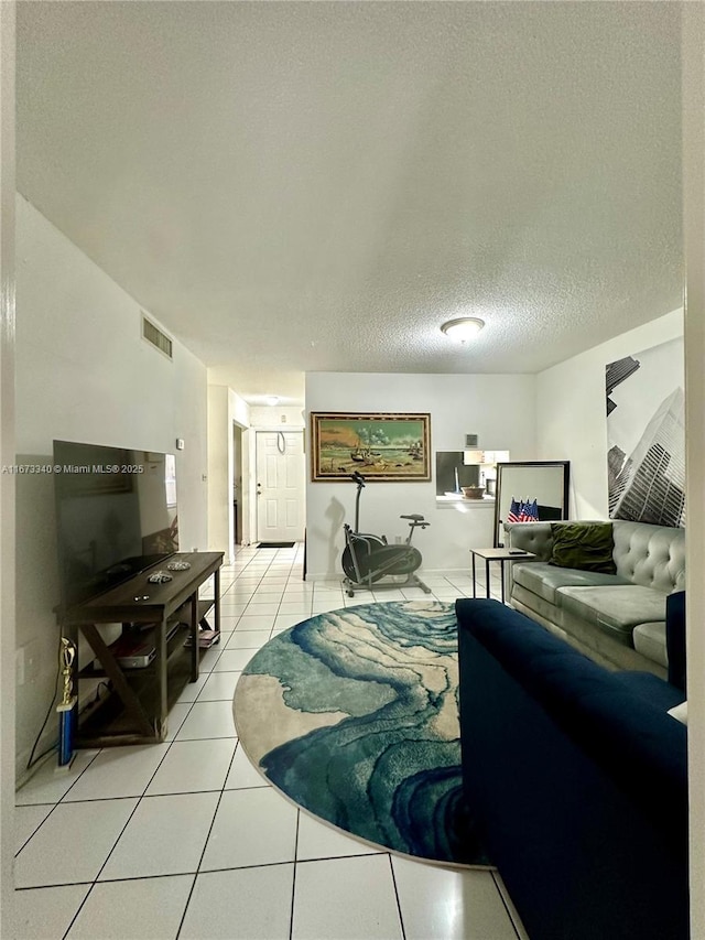 living area with light tile patterned floors, a textured ceiling, and visible vents