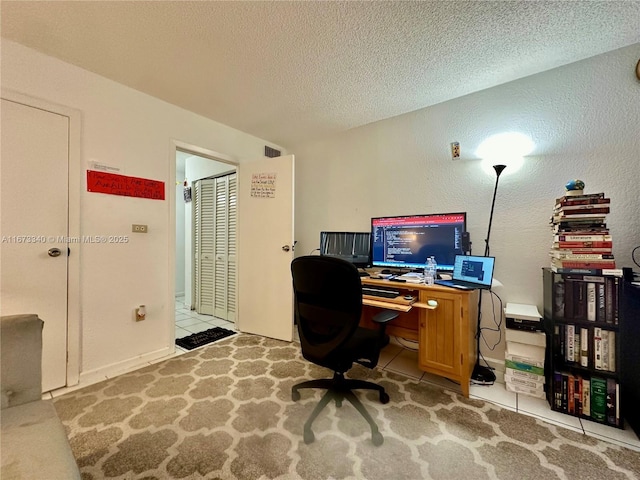 tiled office space with a textured ceiling, a textured wall, and visible vents