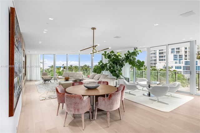 dining room featuring an inviting chandelier, expansive windows, and light wood-type flooring