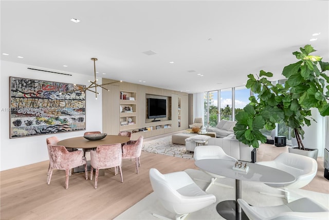 living room with light hardwood / wood-style floors, an inviting chandelier, and a wall of windows