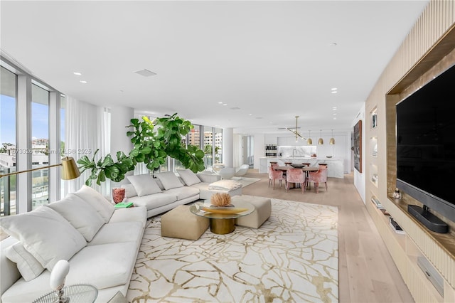 living room featuring a wall of windows, sink, and light hardwood / wood-style flooring