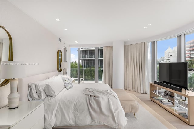 bedroom with floor to ceiling windows, light wood-type flooring, and multiple windows