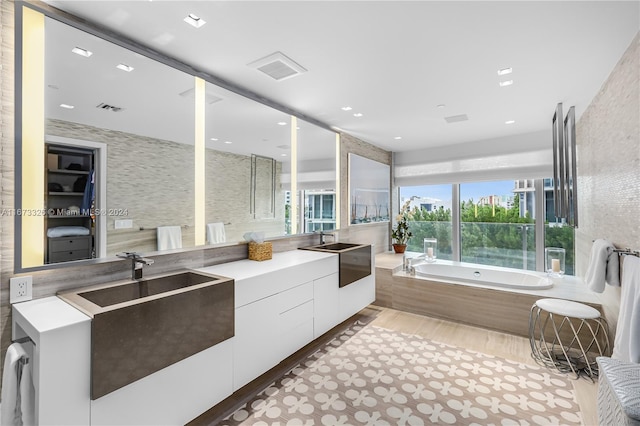 bathroom with a bathing tub, vanity, and wood-type flooring