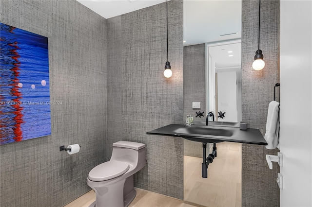 bathroom featuring hardwood / wood-style floors, toilet, tile walls, and sink