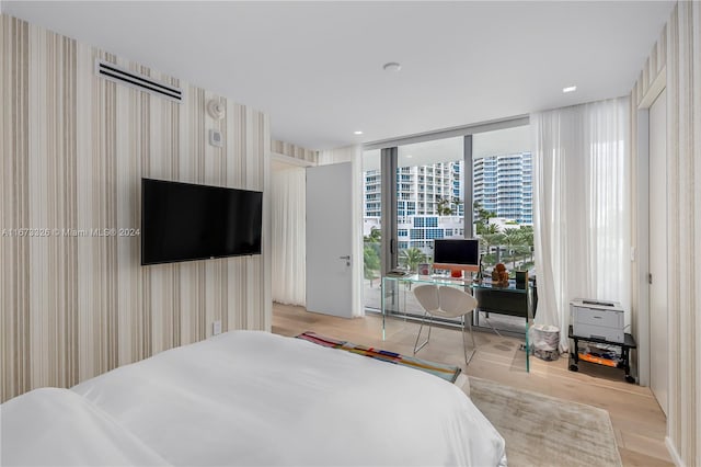 bedroom with a wall of windows and light wood-type flooring