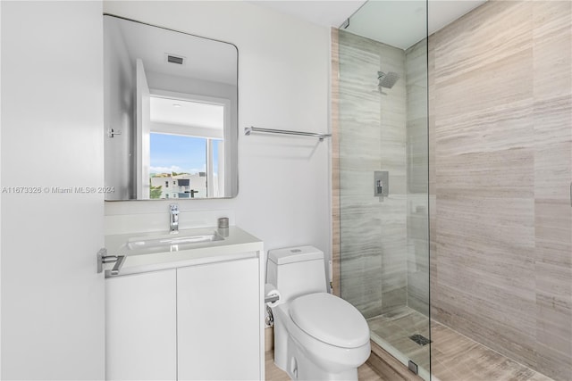 bathroom with a shower with door, vanity, and toilet