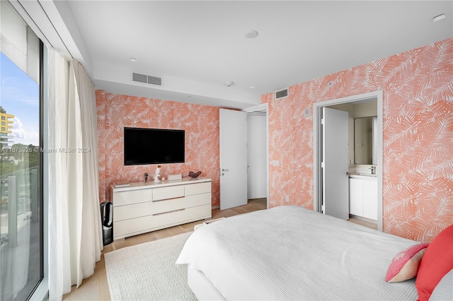 bedroom with ensuite bath and light wood-type flooring