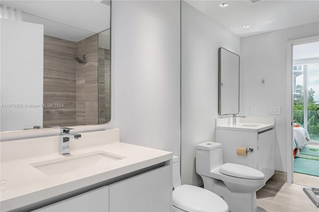 bathroom featuring tiled shower, hardwood / wood-style floors, vanity, and toilet