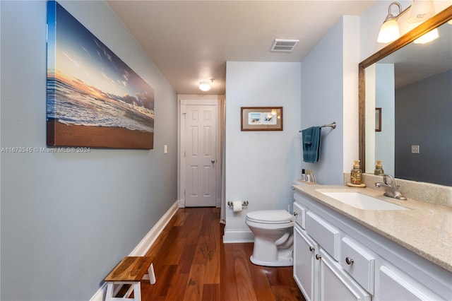 bathroom featuring wood-type flooring, vanity, and toilet