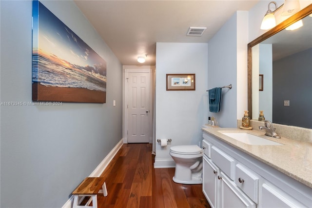 bathroom featuring toilet, baseboards, visible vents, wood finished floors, and vanity