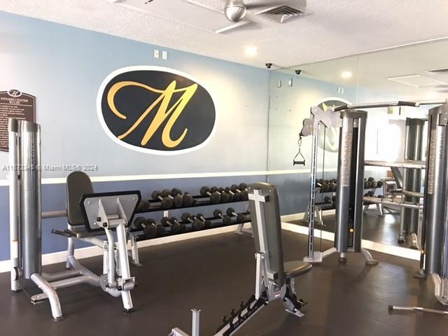 exercise room featuring baseboards, a textured ceiling, and visible vents