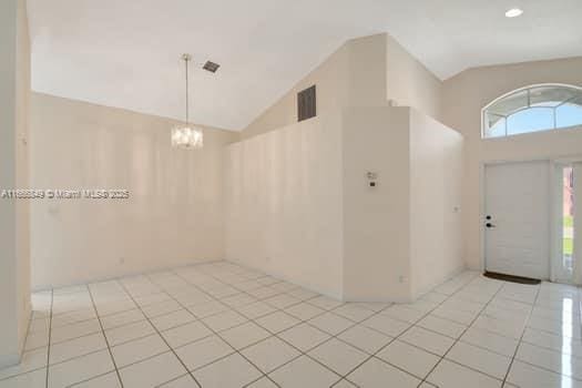 entrance foyer with high vaulted ceiling, light tile patterned floors, and a notable chandelier