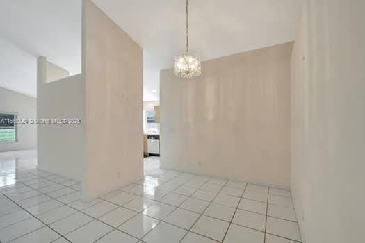 spare room featuring an inviting chandelier and light tile patterned floors