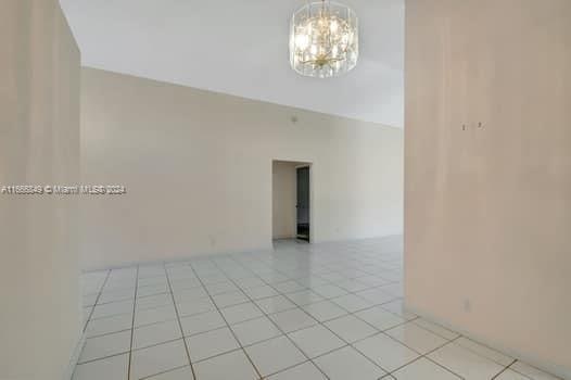 tiled spare room with an inviting chandelier