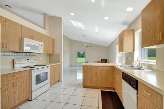 kitchen with kitchen peninsula, white appliances, ceiling fan, sink, and lofted ceiling