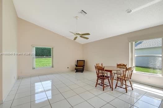 tiled dining space with ceiling fan and lofted ceiling