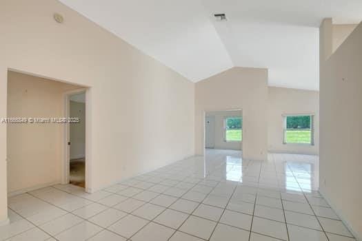 empty room featuring light tile patterned floors and lofted ceiling