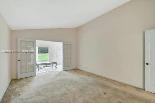 carpeted spare room featuring lofted ceiling
