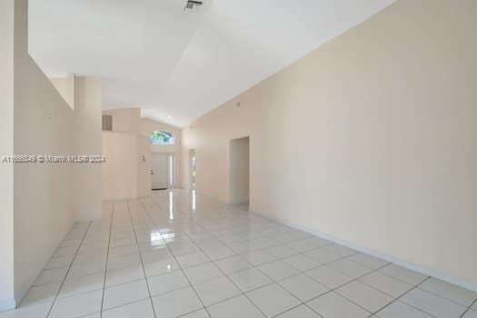 unfurnished room with vaulted ceiling and light tile patterned flooring