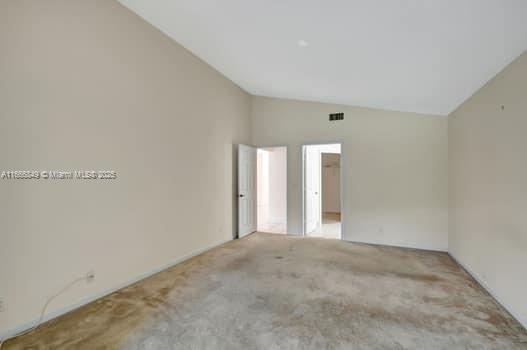 empty room with light carpet, french doors, and vaulted ceiling