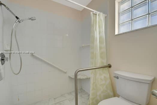 bathroom featuring a shower with curtain and toilet