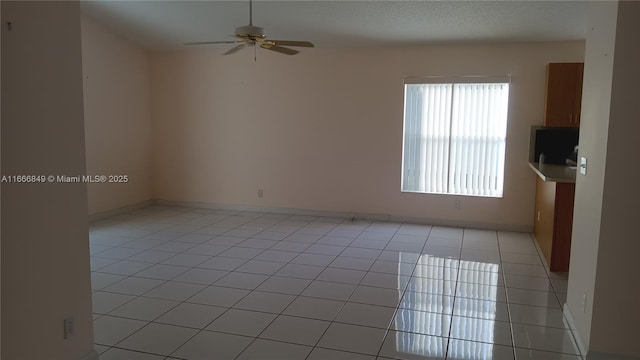 spare room with light tile patterned floors and a ceiling fan