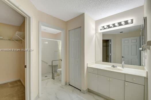 bathroom featuring vanity, a textured ceiling, and a shower with shower door