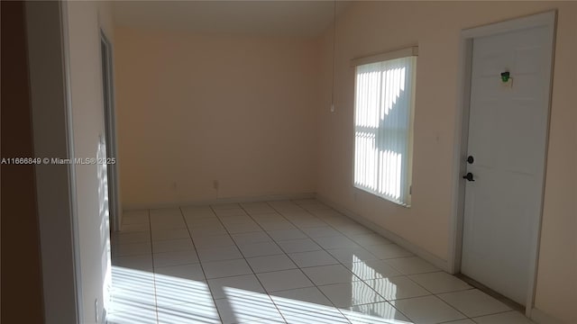 empty room with light tile patterned floors and a healthy amount of sunlight