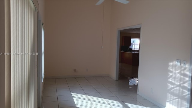 empty room with baseboards, a ceiling fan, and light tile patterned flooring