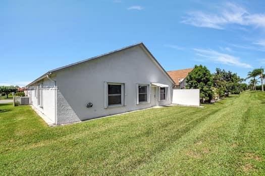 rear view of property with a lawn and stucco siding