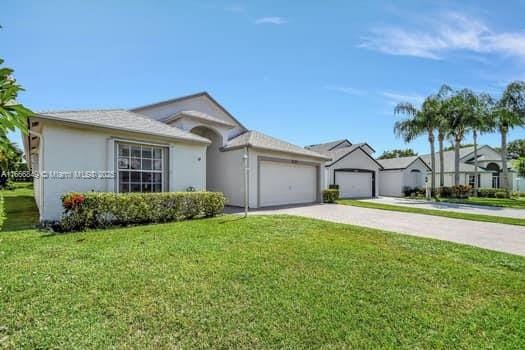 single story home featuring stucco siding, a front lawn, driveway, and an attached garage