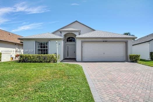 single story home with a front yard, decorative driveway, stucco siding, and a garage