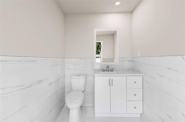 bathroom featuring vanity, tile walls, and toilet