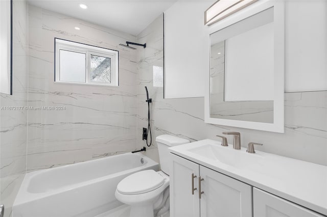 full bathroom with vanity, tiled shower / bath combo, toilet, and tile walls