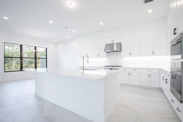 kitchen featuring an island with sink, white cabinets, stainless steel gas stovetop, and sink