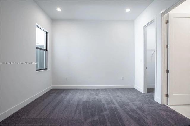 unfurnished room with dark colored carpet