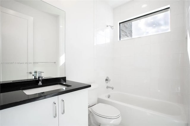 full bathroom featuring tiled shower / bath, vanity, and toilet