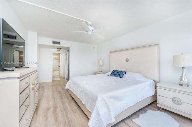 bedroom with light hardwood / wood-style flooring, ensuite bath, ceiling fan, and a textured ceiling